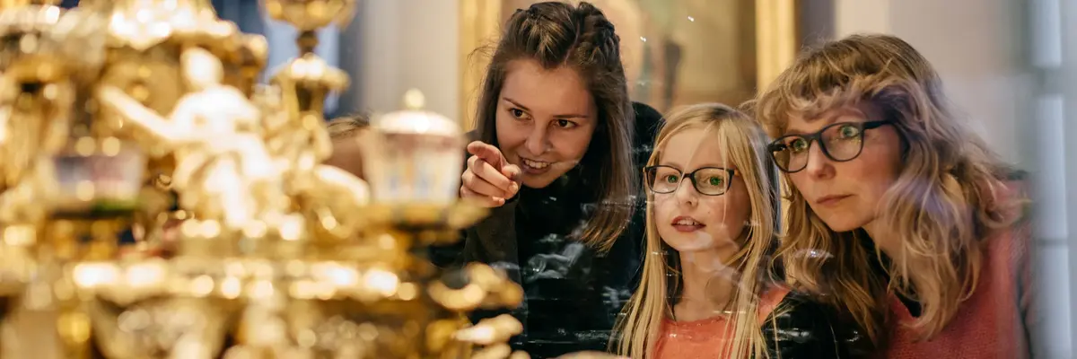 Zwei Erwachsene und ein Kind betrachten ein Objekt