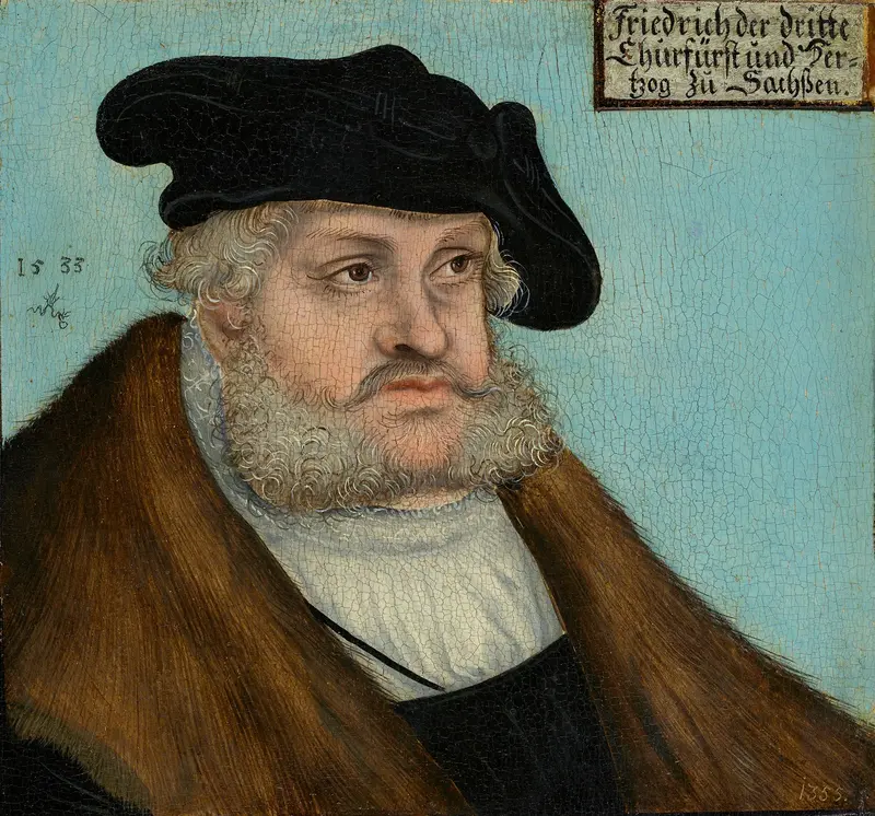 Portrait eines Mannes mit Mütze und Mantel vor hellblauem Hintergrund