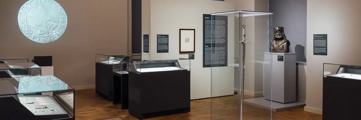 Ausstellungsraum mit Vitrinen und einer Wandprojektion