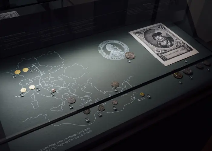 Vitrine mit Münzen, einer Zeichnung und einer Reisekarte