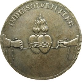 Münze, darauf Hände zweier Personen, die zwei Herzen zusammenschnüren
